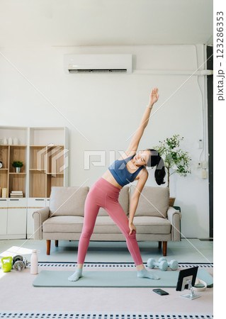 A young woman practices yoga and stretching with a mat and gym props, showcasing wellness, motivation, 123286353