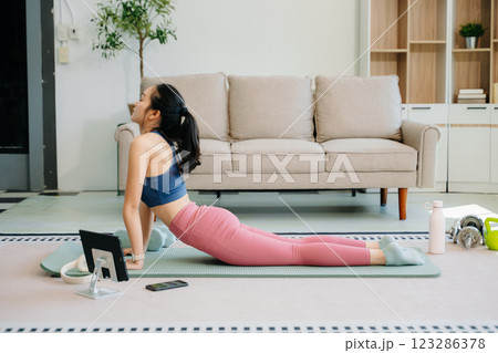 A young woman practices yoga and stretching with a mat and gym props, showcasing wellness, motivation, 123286378