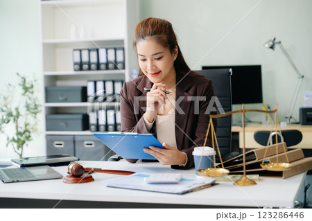 Confident lawyer working on legal analysis at a modern office desk, featuring scales of justice, a gavel 123286446