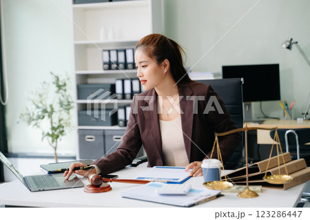 Confident lawyer working on legal analysis at a modern office desk, featuring scales of justice, a gavel Confident lawyer working on legal analysis at a modern office desk, featuring scales of justice, a gavel 123286447