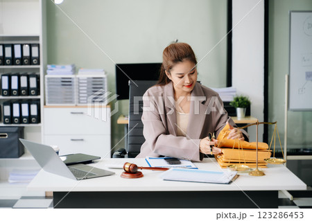 Confident lawyer working on legal analysis at a modern office desk, featuring scales of justice, a gavel Confident lawyer working on legal analysis at a modern office desk, featuring scales of justice, a gavel 123286453