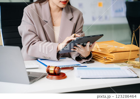 Confident lawyer working on legal analysis at a modern office desk, featuring scales of justice, a gavel 123286464