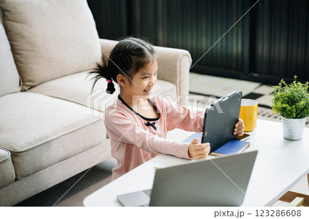 Adorable young girl concentrating on drawing and learning at home Adorable young girl concentrating on drawing and learning at home 123286608