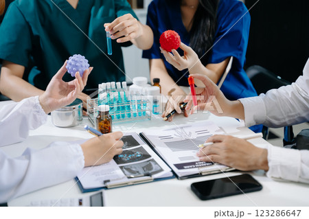 Medical team having a meeting with doctors in white lab coats and surgical scrubs seated Medical team having a meeting with doctors in white lab coats and surgical scrubs seated 123286647