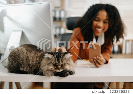 Businesswoman and her office cat, highlighting a relaxed and productive workspace. Perfect for themes of office life, pets 123286828