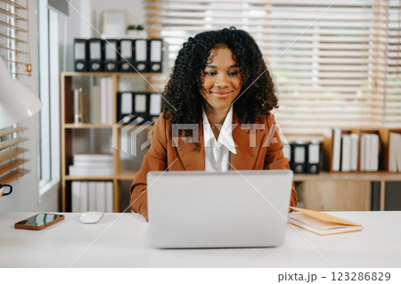 Businesswoman Analyzing Finance on Tablet and Laptop at modern Office Desk tax 123286829