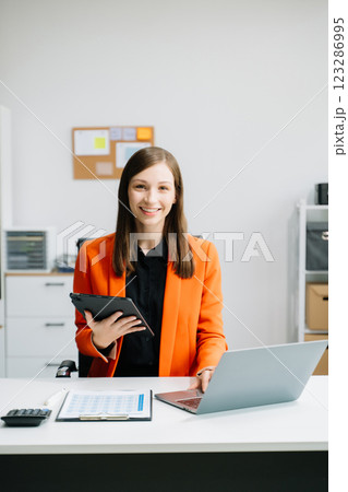 Business woman using tablet and laptop for doing math finance on an office desk, tax 123286995