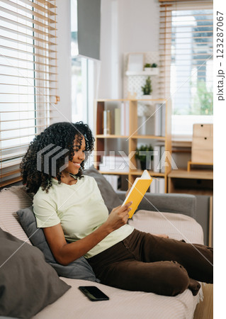 frican woman using the smartphone and tablet on the sofa at home 123287067