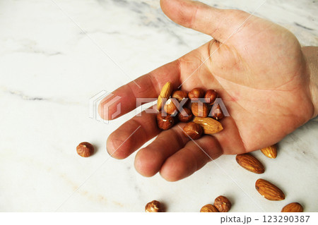 Nuts, almonds and fduk on the palm of your hand on a white background with space for copyspace text Nuts, almonds and fduk on the palm of your hand on a white background with space for copyspace text 123290387