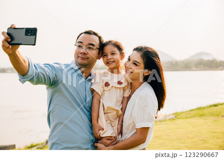Asian family taking selfie picture with smartphone outdoor nature park, Happy smile father mother and child daughter taking photo with mobile phone together, Tourist lifestyle people leisure activity 123290667
