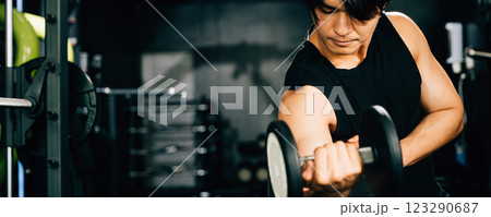 Asian man Muscular guy lifting dumbbell while sitting on bench gym, men using dumbbell during workout pumping up bicep muscle at fitness gym, workout healthy lifestyle concept 123290687