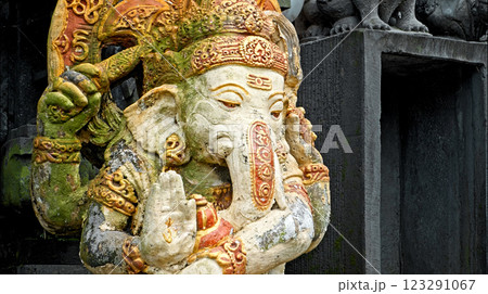 An old stone statue of Ganesha covered with moss, standing on the street An old stone statue of Ganesha covered with moss, standing on the street 123291067
