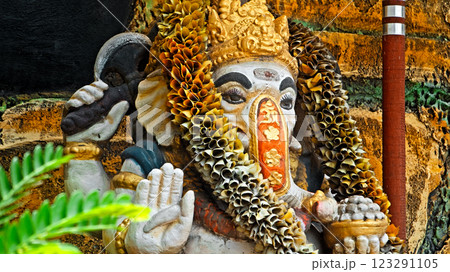 An old stone statue of Ganesha covered with moss, standing on the street 123291105