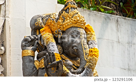 An old stone statue of Ganesha covered with moss, standing on the street An old stone statue of Ganesha covered with moss, standing on the street 123291106