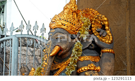 An old stone statue of Ganesha covered with moss, standing on the street 123291113