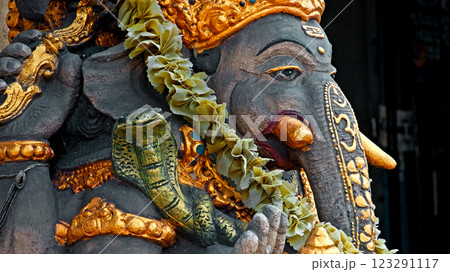 An old stone statue of Ganesha covered with moss, standing on the street An old stone statue of Ganesha covered with moss, standing on the street 123291117