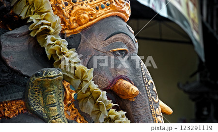 An old stone statue of Ganesha covered with moss, standing on the street 123291119