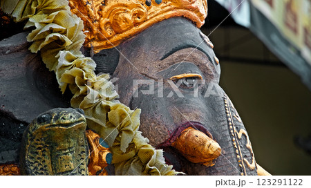 An old stone statue of Ganesha covered with moss, standing on the street 123291122