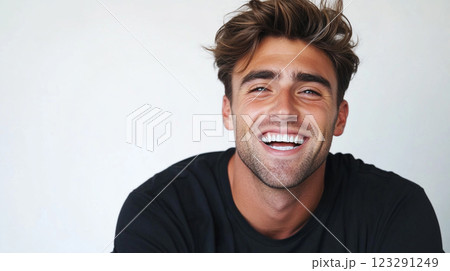 Bright smile of a young man with tousled brown hair, radiates joyful energy, isolated on a white backdrop. A picture of happiness. 123291249