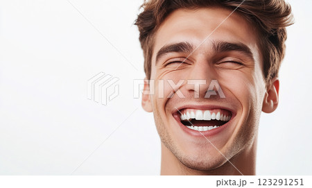 A young man, light brown hair, captured mid-laugh, eyes closed, showcasing bright white teeth, isolated against a white backdrop. 123291251