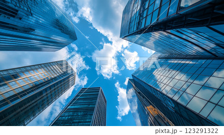 Skyscrapers reach for the sky, their glass facades mirroring the blue sky and fluffy white clouds in a dance of architectural brilliance. 123291322
