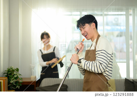 Cheerful young couple having fun while cleaning their home. Daily household chores concept 123291888