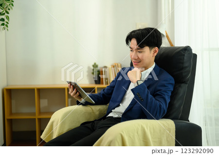 Pleased young entrepreneur using digital tablet on armchair Pleased young entrepreneur using digital tablet on armchair 123292090