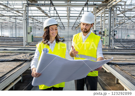 Engineers at the greenhouse construction site scrutinizing a construction plan Engineers at the greenhouse construction site scrutinizing a construction plan 123292899