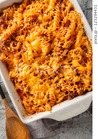 Delicious sloppy joe casserole with meat, pasta, vegetables and sauce and lots of cheese close-up in baking dish on table. Vertical top view 123294431