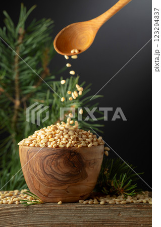 Pine nuts is poured in a wooden bowl. 123294837