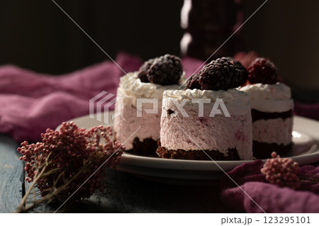 Delicious cream cakes with frozen blackberries on a white plate, close-up 123295101