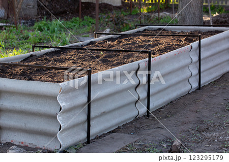 Permaculture raised warm bed made of slate with branches at the base in the garden 123295179