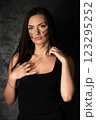 Beautiful woman in a black top applying camouflage military makeup to her body 123295252