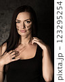 Beautiful woman in a black tank top applying camouflage military makeup to her body 123295254