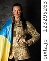 Beautiful military woman in military uniform with camouflage makeup on her face with Ukrainian flag 123295263