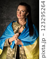 Beautiful young military woman in military uniform with camouflage makeup on her face with Ukrainian flag 123295264