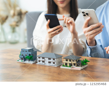 住宅模型の前でスマホを見るカップル　部屋探し　不動産投資 123295468