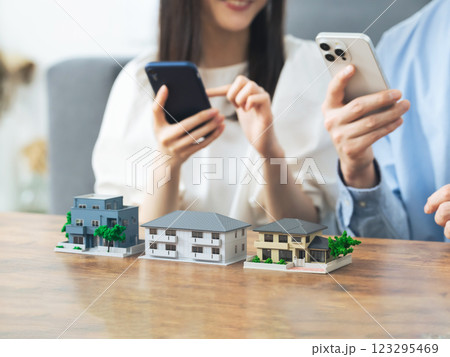 住宅模型の前でスマホを見るカップル　部屋探し　不動産投資 123295469