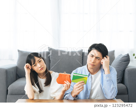 財布と預金通帳を持って悩むカップル 123295472