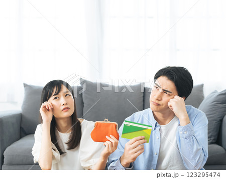 財布と預金通帳を持って悩むカップル 123295474