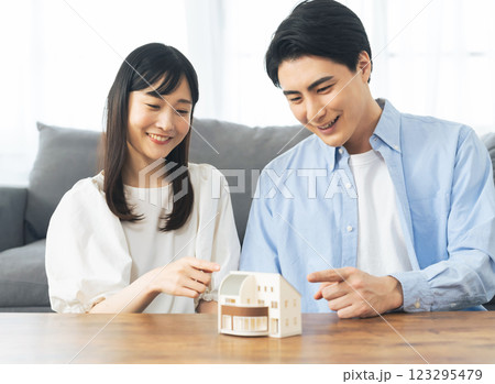 住宅模型を見ながら笑顔で話すカップル 123295479