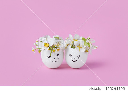White eggs with funny face with spring pear and strawberry flowers on a pink background. Happy Easter concept. Greeting card. 123295506