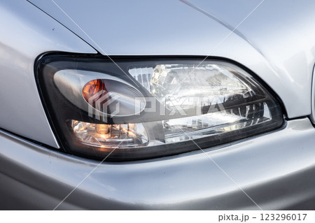Front headlight view of car in silver color after cleaning and detailing with washer before sale. 123296017