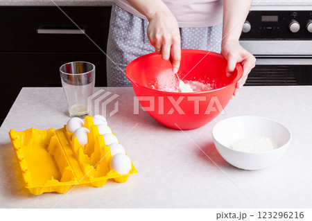 Making cupcakes at home. A woman prepares Easter cakes in the kitchen, beating the dough with a whisk Making cupcakes at home. A woman prepares Easter cakes in the kitchen, beating the dough with a whisk 123296216