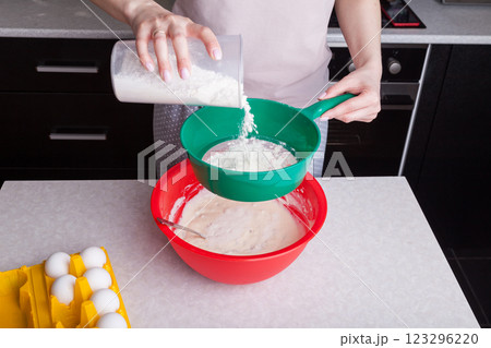 Making cupcakes at home. A woman prepares Easter cakes in the kitchen, pouring flour through a sieve. Making cupcakes at home. A woman prepares Easter cakes in the kitchen, pouring flour through a sieve. 123296220