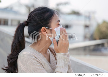 Young woman wearing a mask outdoors, expressing concern about pollution and air quality. 123297352