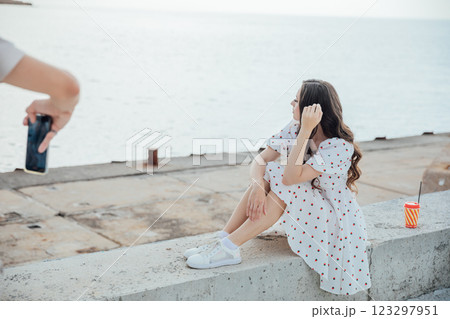 Man taking pictures of beautiful woman in dress on beach Man taking pictures of beautiful woman in dress on beach 123297951