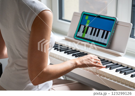 Young woman learning to play the keyboard at home using an interactive app. Using mobile apps for self-study concept Young woman learning to play the keyboard at home using an interactive app. Using mobile apps for self-study concept 123299126