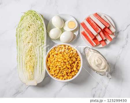 Canned corn, surimi sticks, half of napa cabbage, boiled eggs and mayo on a marble countertop. 123299430