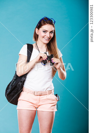 Tourist woman looking through binoculars on blue 123300981